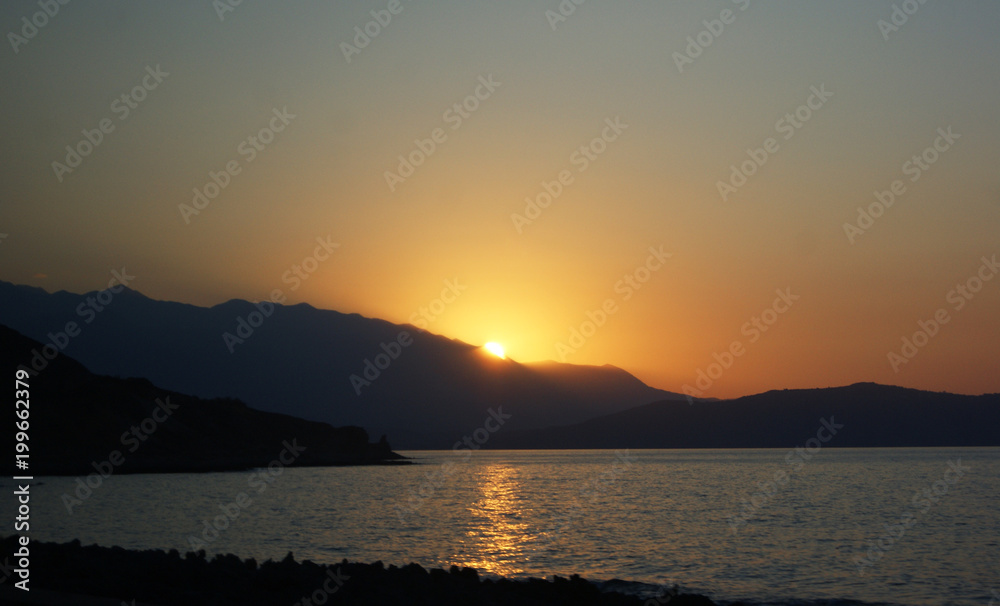 sunset at the sea, behind the hills