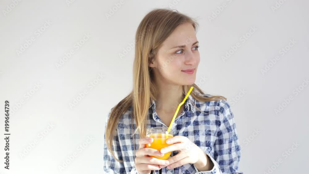 Girl smiles and drinks orange juice through a straw Girl smiles and drinks orange juice through a straw