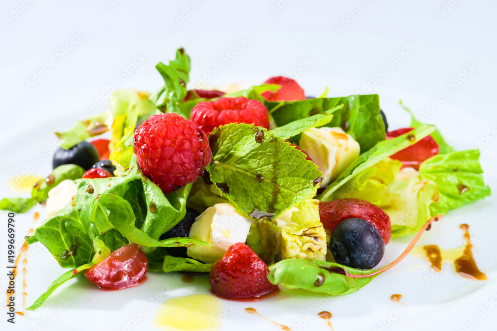 Appetizing fresh vegetarian salad with different berries, tomatoes, meat, basil leaves and sauce, close-up. For menu design Appetizing fresh vegetarian salad with different berries, tomatoes, meat, basil leaves and sauce, close-up. For menu design