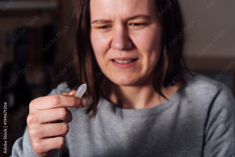 Young sad woman holding suppository StockFoto Adobe Stock