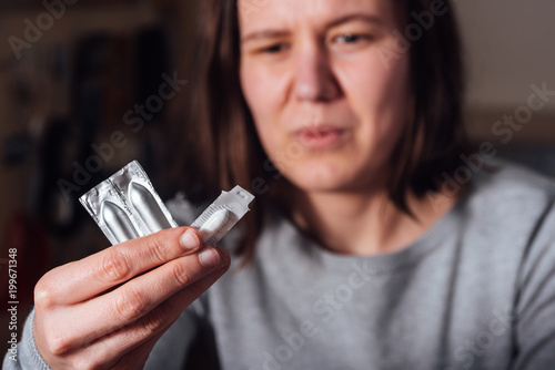 Young sad woman holding suppository