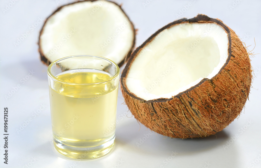 Coconut oil in a cup with split coconuts on a white background. Coconut oil in a cup with split coconuts on a white background.