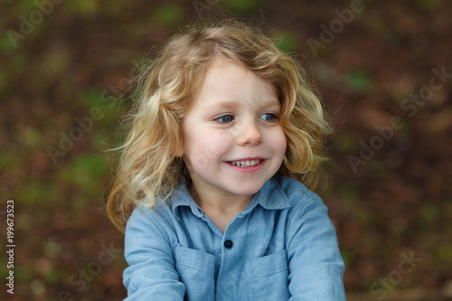 Happy child with long blond hair enjoying the nature