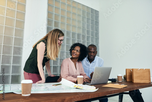 Smiling coworkers working on a laptop together in an office