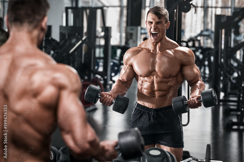 Muscular man working out in gym doing exercises, strong male naked torso abs