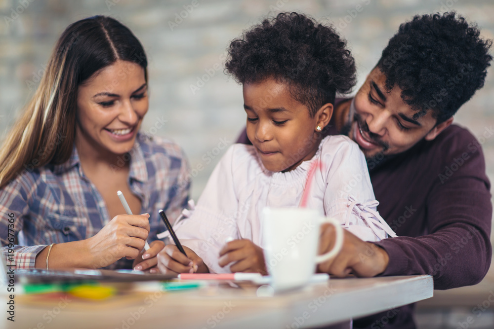 Mom and dad drawing with their daughter. Girl and mixed race parents having fun at home. Mom and dad drawing with their daughter. Girl and mixed race parents having fun at home.