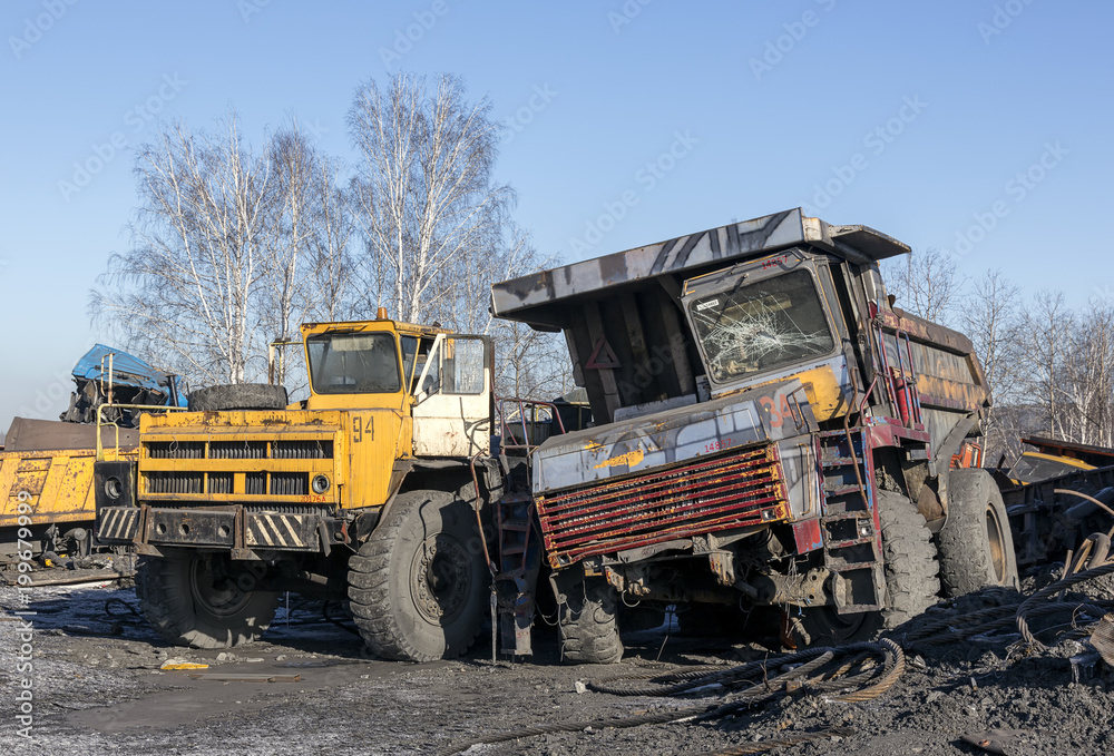 Old big trucks in a dump near a coal mine.