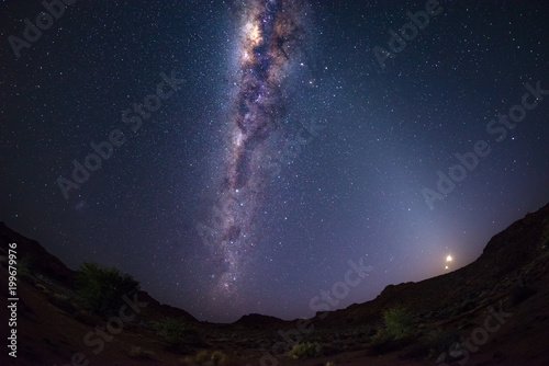 Starry sky and Milky Way arch with moon in the Namib desert in Namibia, Africa. The Small Magellanic Cloud on the left hand side.