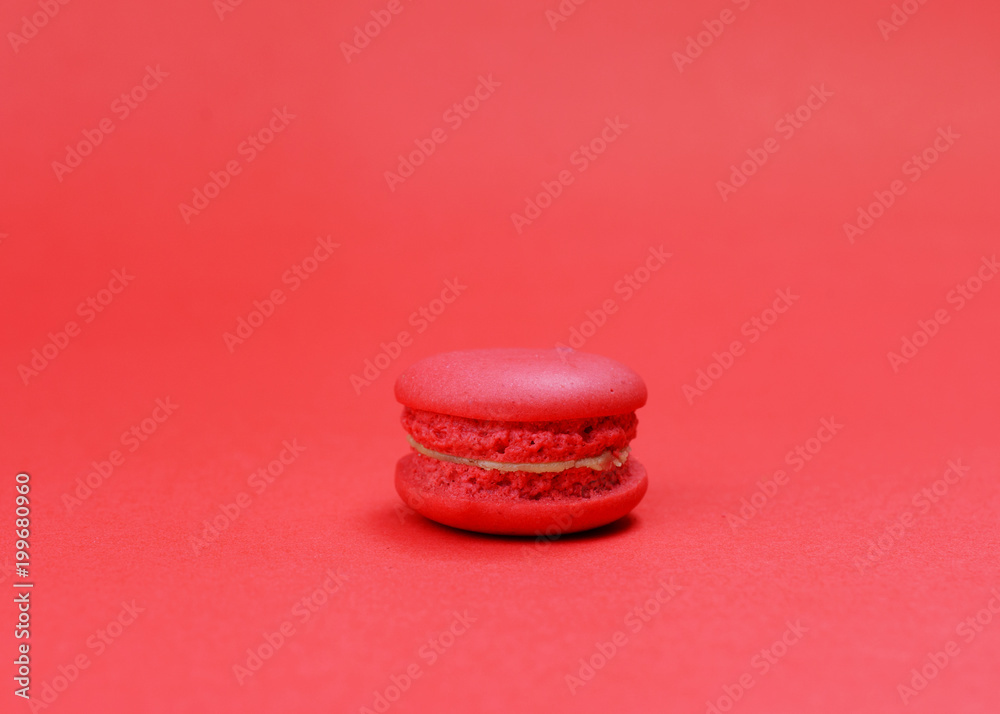 Single red macaroons cookie on red backgrounds Single red macaroons cookie on red backgrounds
