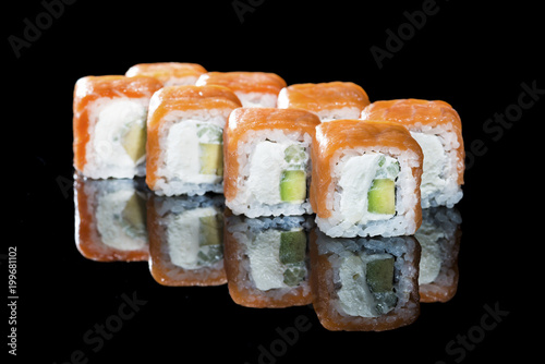 Delicious Philadelphia sushi rolls with rice, avocado, cream cheese and salmon on dark background