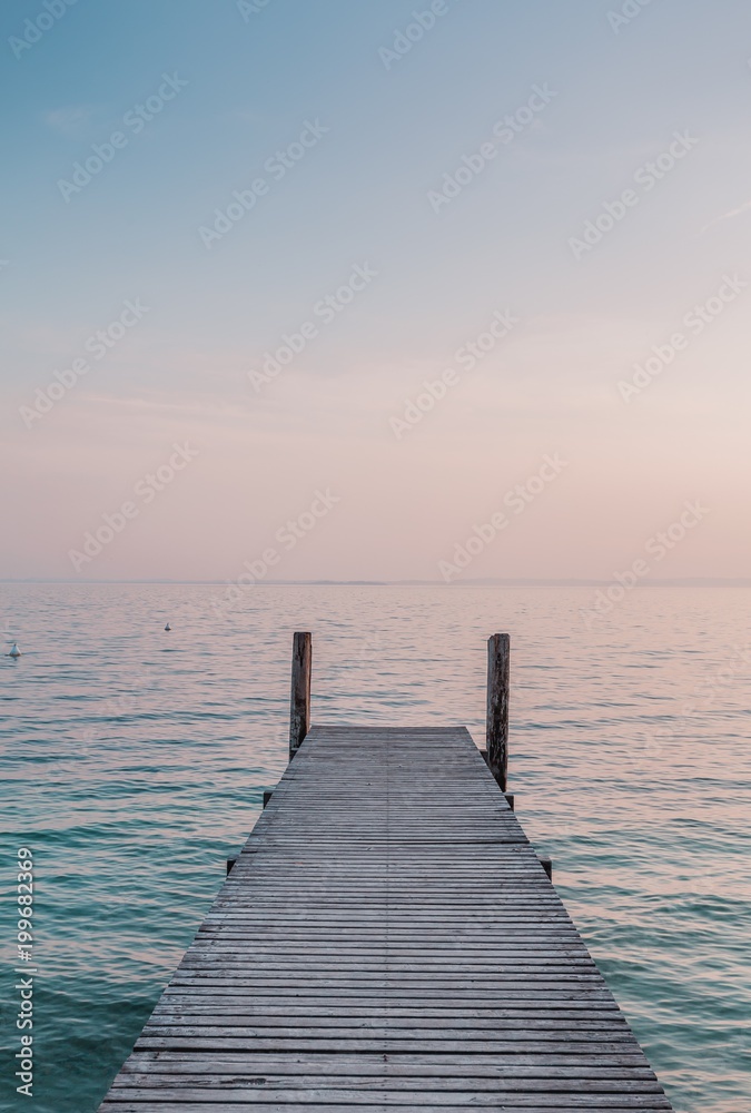 View of a wooden pier on the seashore with clear morning sky and sea with turquoise water.