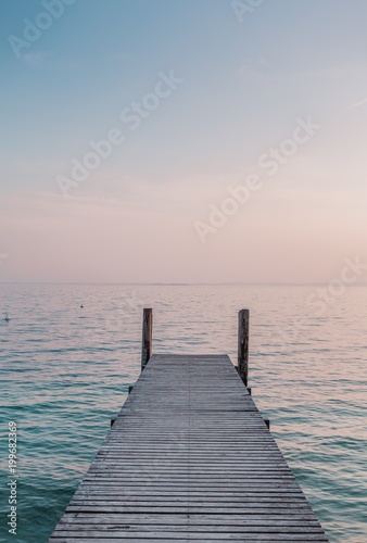 View of a wooden pier on the seashore with clear morning sky and sea with turquoise water.