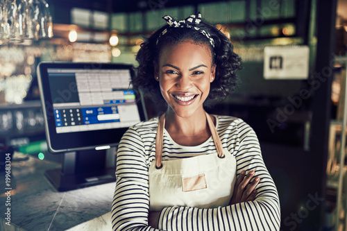 Smiling young African waitress behind the counter of a restauran photo