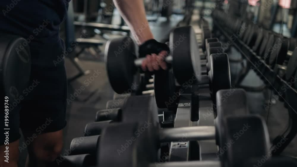 strong man's hand takes a heavy dumbbell in gym, close up macro indoor sport guy strong man's hand takes a heavy dumbbell in gym, close up macro indoor sport guy