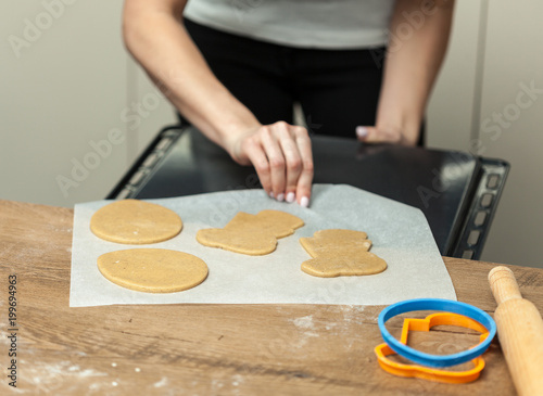 Woman put raw dough in oven in kitchen closeup.