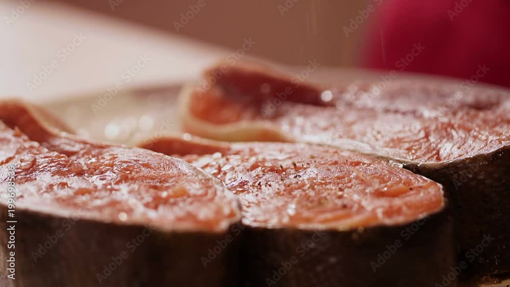 The woman strews pepper red stakes of fish. cook salmon fillets stock footage food. Slow-motion shot. Close up. Beautiful shooting of food. cook The woman strews pepper red stakes of fish. cook salmon fillets stock footage food. Slow-motion shot. Close up. Beautiful shooting of food. cook