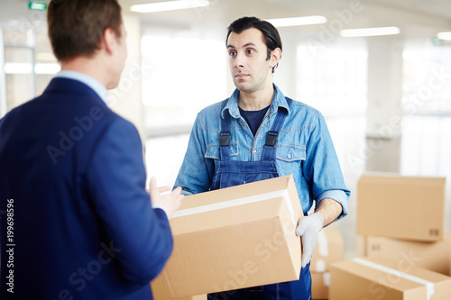 Gloved worker in uniform talking to businessman about where to remove boxes with office supplies © pressmaster