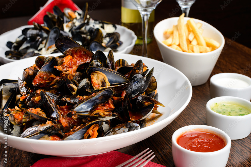 Delicious Shellfish Traditional Mussels with tomato sauce on the table. Romantic dinnerat a restaurant Delicious Shellfish Traditional Mussels with tomato sauce on the table. Romantic dinnerat a restaurant
