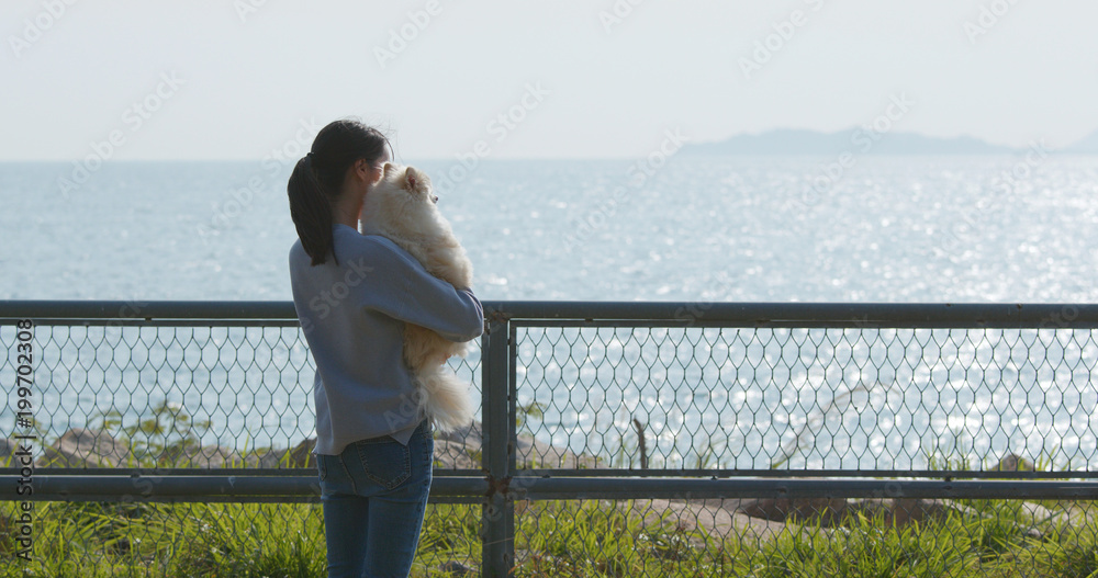 Woman hugging her dog and looking at the sea Woman hugging her dog and looking at the sea