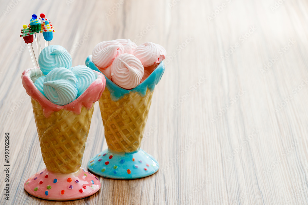 blue and pink meringue in the pink and blue cones with cupcakes on wood background or happy mothers day