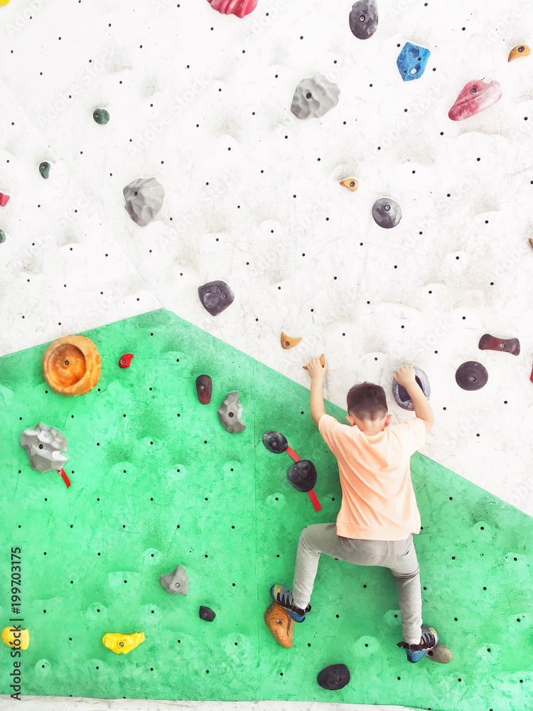 boy climbing rock wall  - obrazy, fototapety, plakaty 