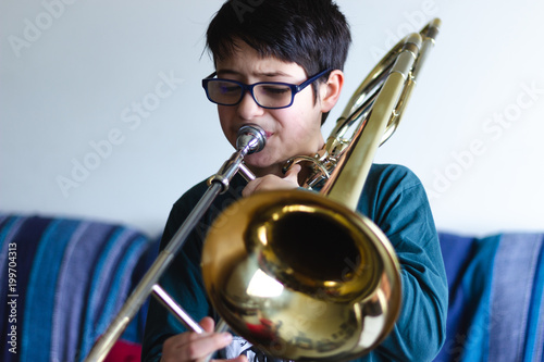 Menino a tocar trombone em casa. photo