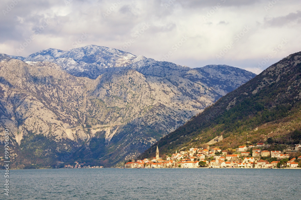 Cloudy Mediterranean landscape with  sunny seaside city. Montenegro, view of Bay of Kotor and ancient town of Perast on  spring day