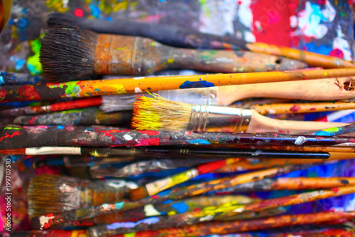 Paint brushes of different sizes, stained by vivid colors, close-up