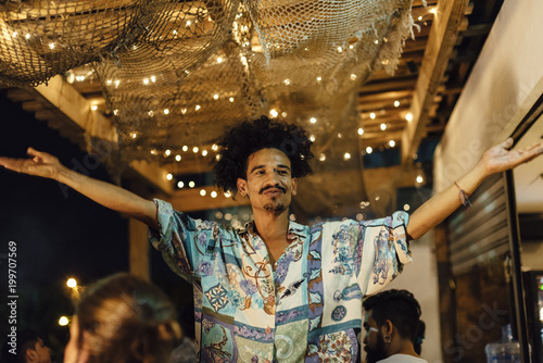 Indian ethnicity afro hair DJ raise his hands to invite people to dance at tropical party in the caribbean sea in Santa Marta, Colombia photo