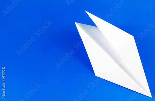 White paper airplane on bright blue background