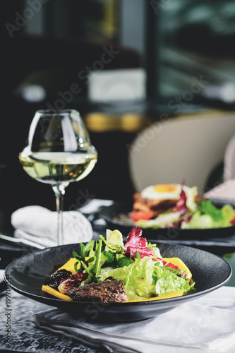 Картината върху платно Delicious meat dish with salad leaves on the table in the restaurant