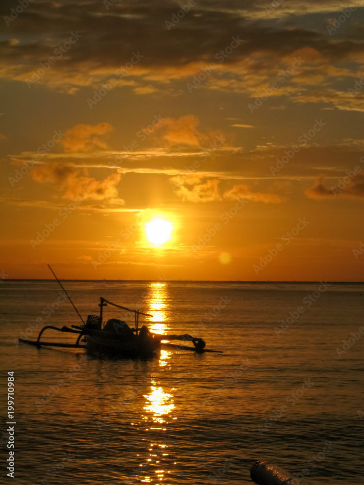 Beautiful sunset in orange colour and a fisherman boat at Bali 