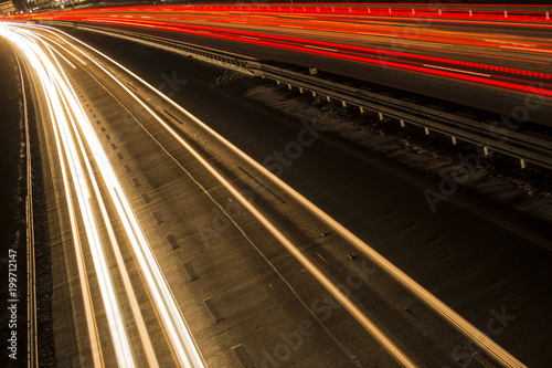 Night scene of motion blurred light tracks glowing to the darkness of highway traffic to the city just after sunset. Creative long time exposure diagonal composed photography.