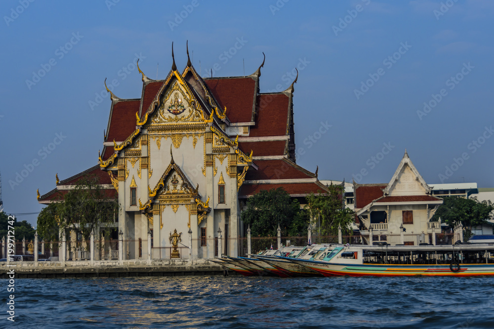 Buddhist temple and passenger boats on the river Chao Phraya Bangkok Thailand