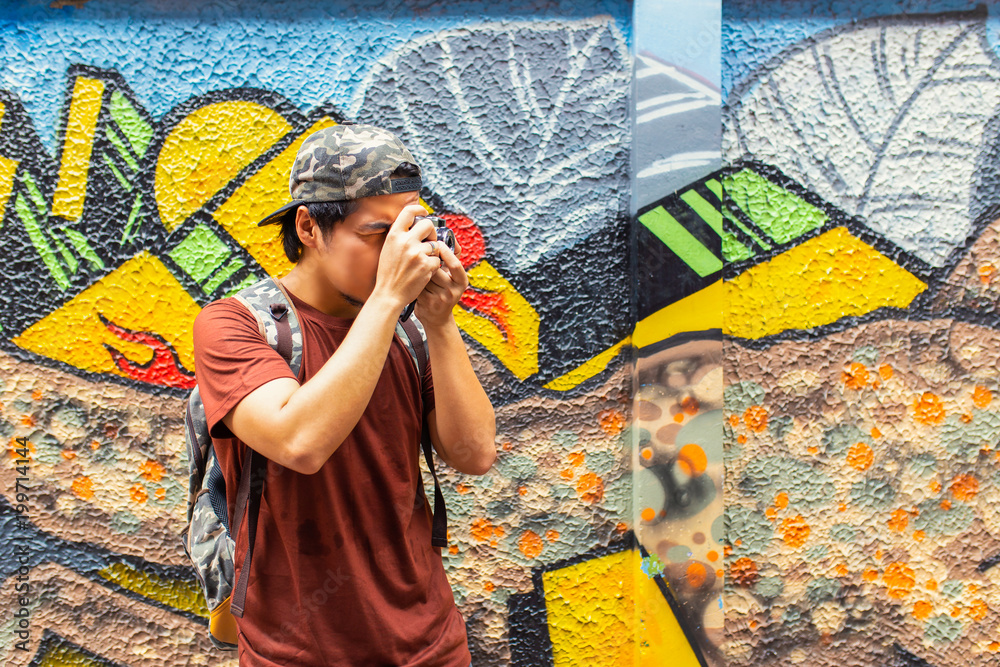 Obraz premium Młoda azjatycka turystyka podróżnicza za pomocą kamery filmowej robi zdjęcie w street art w Bangkoku.