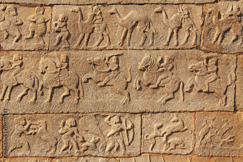 Stone bas-reliefs on the walls in Temples Hampi. Carving stone ancient background. Carved figures made of stone. Unesco World Heritage Site. Karnataka, India. Beige background.