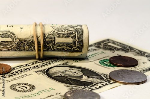 one dollar rolls and some cents, still life with a dollar bill rolls over a white background. symbol of wealth photo