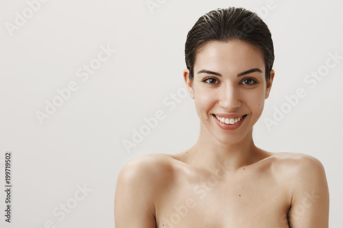 Studio portrait of beautiful woman looking at camera as if in mirror standing naked and smiling broadly, getting out from shower after washing hair, getting dressed for important date