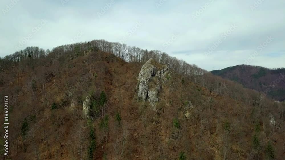 Aerial: Going up in front of hill covered with trees and big rocks. Flying on beautiful sunny spring day. Aerial: Going up in front of hill covered with trees and big rocks. Flying on beautiful sunny spring day.