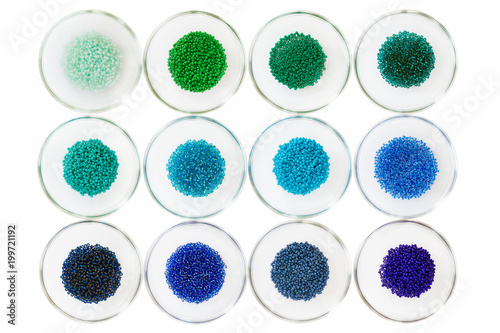 Small seed beads isolated on white in small glass bowls; blue, green and aqua beads displayed in glass bowls