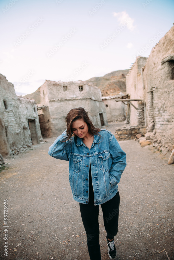 Portrait of an attractive young woman posing close to vintage village. Lifestyle and fashion concept