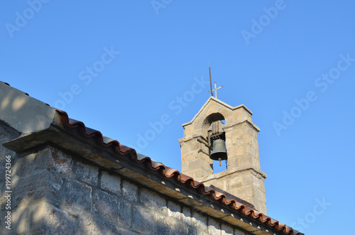 Stone belfry of a small village church and clear blue sky