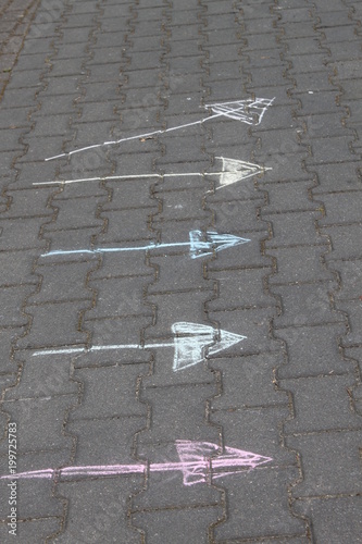 Kolorowe strzałki narysowane kredą na chodniku