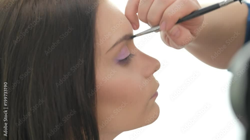 Portrait of young beautiful woman and stylist in make up salon brushing eyebrow Portrait of young beautiful woman and stylist in make up salon brushing eyebrow