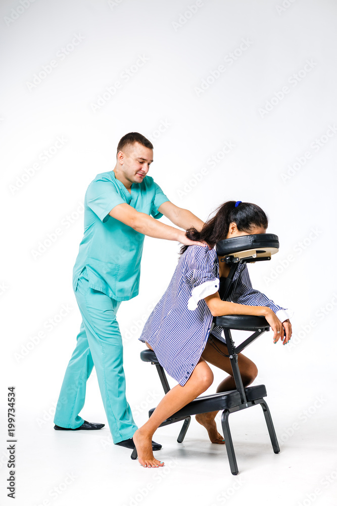 Theme massage and office. Male therapist with blue suit doing back and neck massage for young woman worker, business woman in shirt on massage chair shiatsu Theme massage and office. Male therapist with blue suit doing back and neck massage for young woman worker, business woman in shirt on massage chair shiatsu