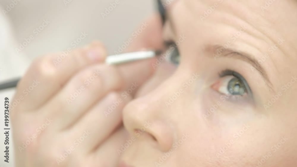 Portrait of young beautiful woman and stylist in make up salon brushing eyelashes holding set of colors Portrait of young beautiful woman and stylist in make up salon brushing eyelashes holding set of colors