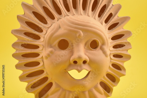 Ceramic Sun Face stock images. Ceramic sun on a yellow background. Sun decoration. Ceramic Sun Lamp. Sun clay lamp