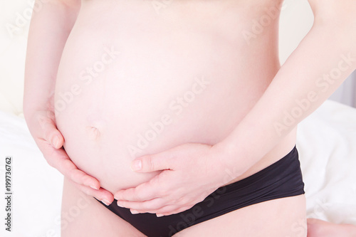 Close-up of pregnant woman with hands over tummy