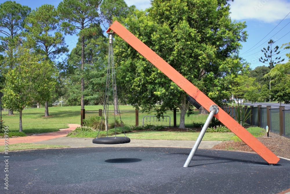 Swing in public park. Tire swing tied with metal chains to metal beam in children's park. Kids park in Australia Swing in public park. Tire swing tied with metal chains to metal beam in children's park. Kids park in Australia