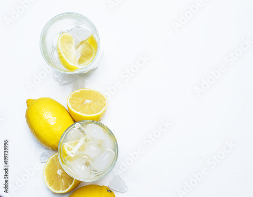 Summer refreshing drink, cold water with ice and lemon, white background, top view